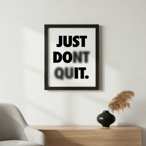תמונת פוסטר עם מסגרת שחורה, מציגה כיתוב "Just Don't Quit" בפונט לבן על רקע שחור, בעיצוב מינימליסטי.