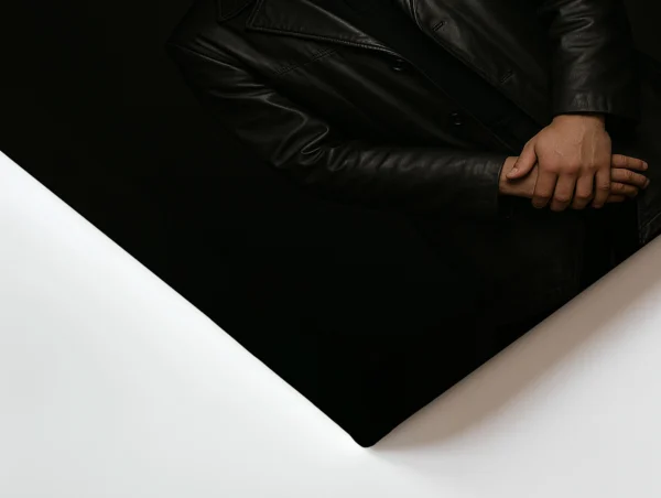 תמונת קנבס של דיוקן גבר צעיר במעיל עור שחור, ידיים שלובות, מבט רציני למצלמה, וטקסט השראה באנגלית על רקע כהה.