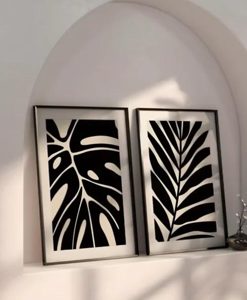 סט שתי תמונות ממוסגרות עם איורים מופשטים של עלי בוטניקה טרופיים בסגנון בוהו.