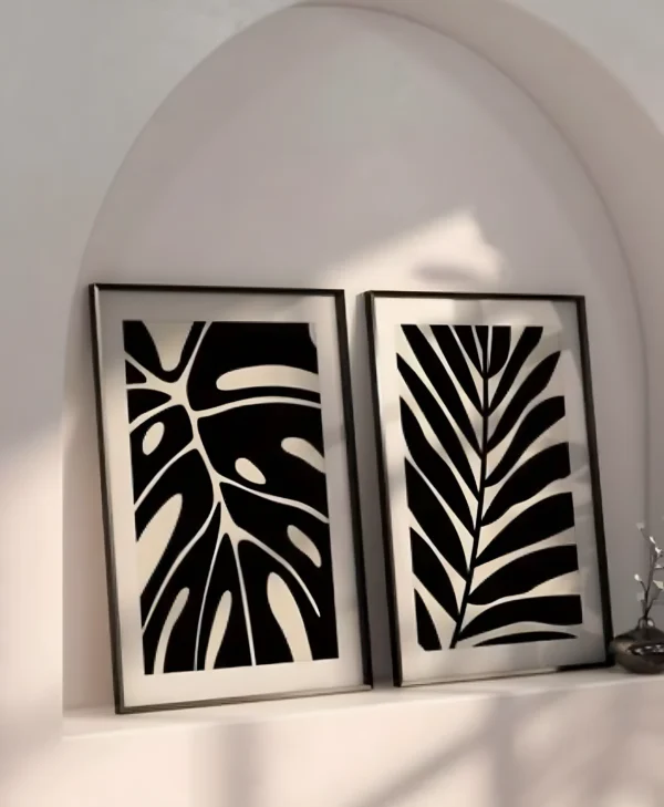 סט שתי תמונות ממוסגרות עם איורים מופשטים של עלי בוטניקה טרופיים בסגנון בוהו.